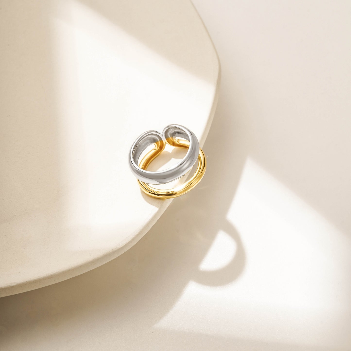 Gold and silver ring with intertwined bands, featuring a smooth and polished finish