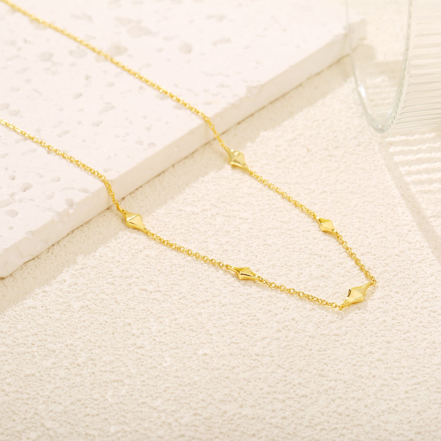 Elegant gold vermeil necklace with geometric kite-shaped charms evenly spaced along a delicate chain