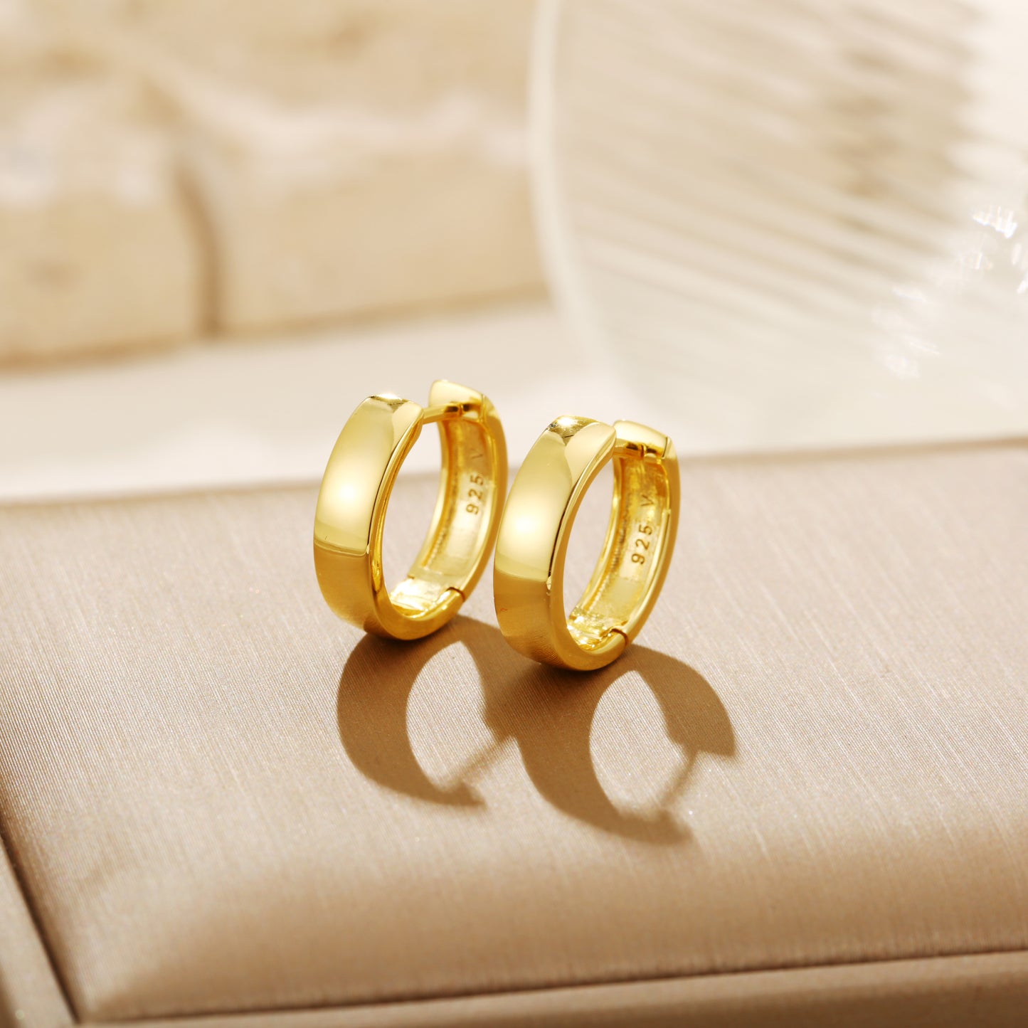 Polished gold vermeil hoop earrings with a smooth, reflective finish and a stamped '925' hallmark indicating sterling silver purity